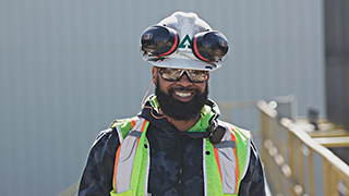 Image of a worker wearing a Ƶ-branded hardhat wearing safety googles and with ear protection worn over his head.